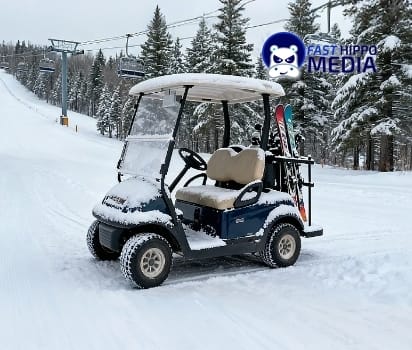 Golf cart covered in snow at a ski slope